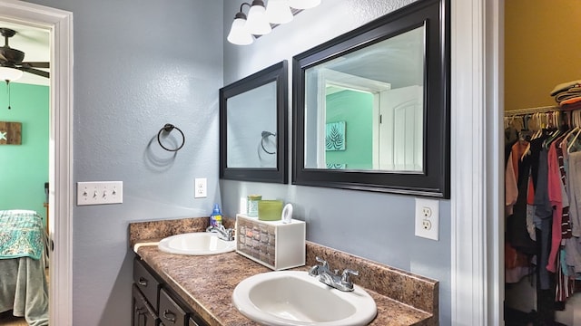 full bathroom with a spacious closet, double vanity, ceiling fan, and a sink