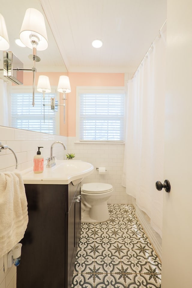 bathroom with tile walls, toilet, a shower with shower curtain, tile patterned floors, and vanity