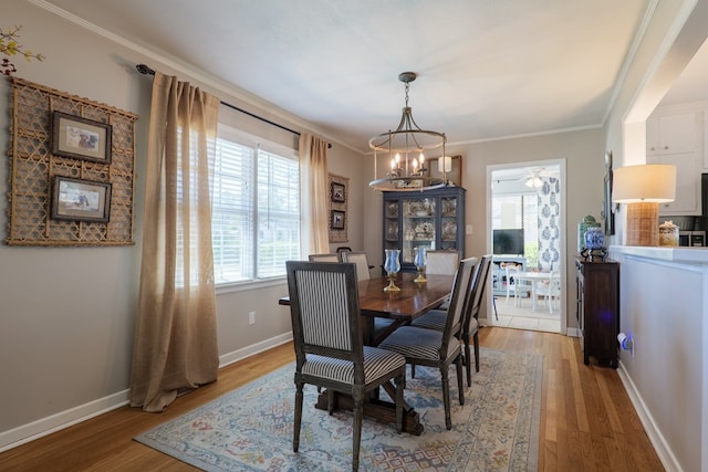 dining room with baseboards, crown molding, and light wood finished floors