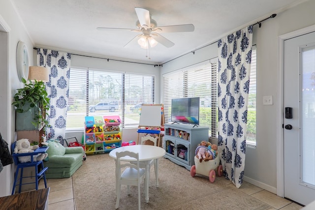 recreation room with a wealth of natural light, baseboards, light tile patterned flooring, and a ceiling fan