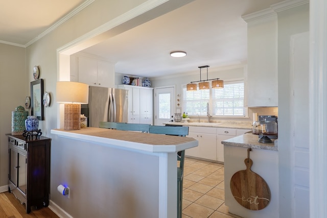 kitchen with a sink, white cabinetry, crown molding, and freestanding refrigerator