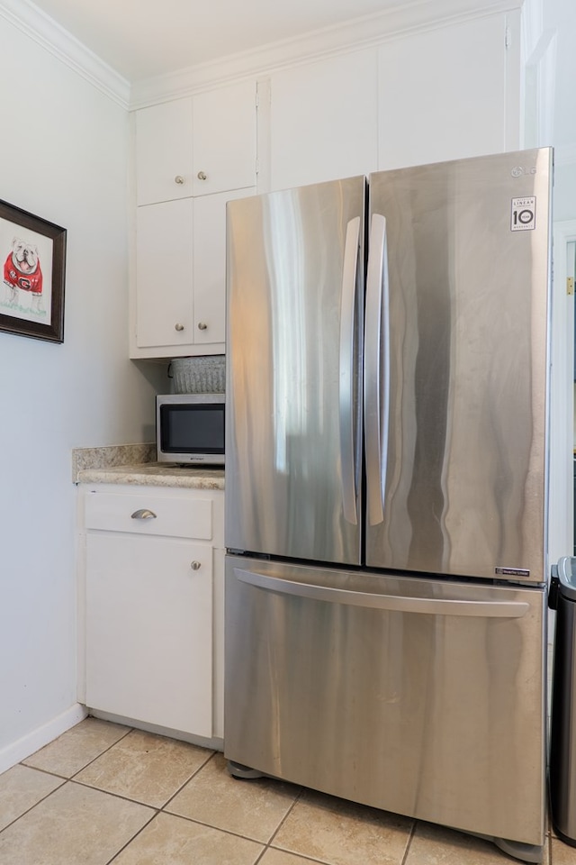 kitchen with light tile patterned floors, baseboards, white cabinets, appliances with stainless steel finishes, and crown molding