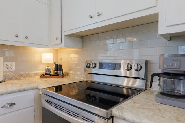 kitchen with white cabinetry, backsplash, light countertops, and stainless steel range with electric cooktop