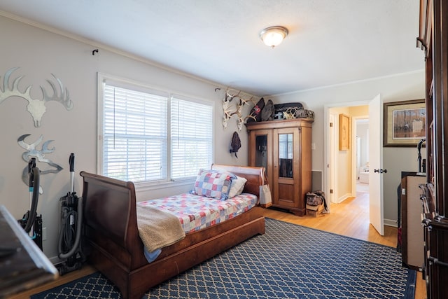 bedroom with light wood finished floors, baseboards, and ornamental molding