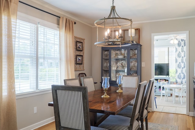 dining area featuring light wood-style flooring, a notable chandelier, baseboards, and ornamental molding