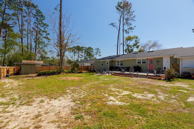 view of yard with an outbuilding, a fenced backyard, a shed, and a patio