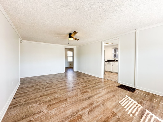 spare room featuring ceiling fan, crown molding, light hardwood / wood-style flooring, and a textured ceiling