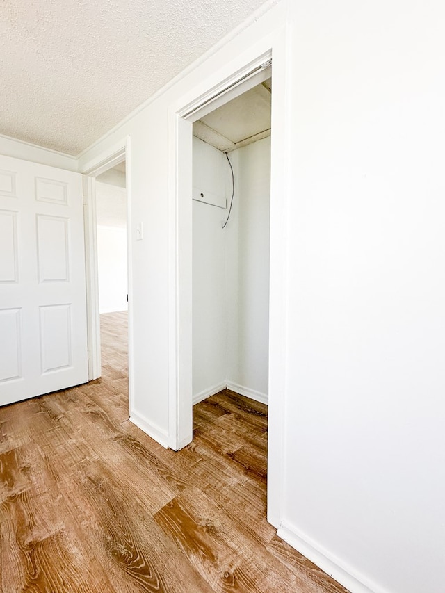 unfurnished bedroom with a textured ceiling, light hardwood / wood-style floors, and a closet