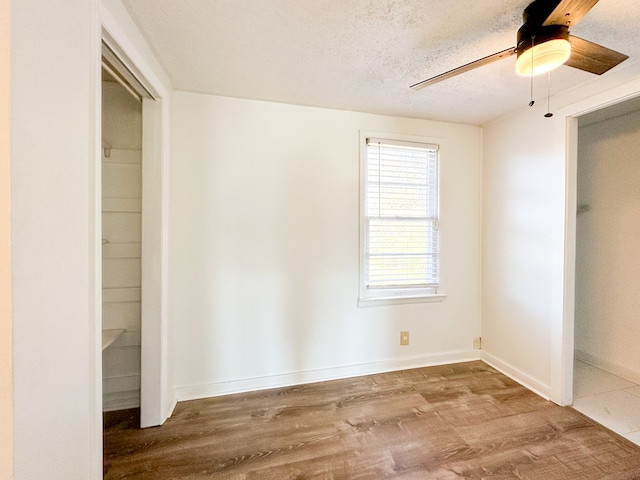 unfurnished bedroom featuring hardwood / wood-style flooring, a textured ceiling, a closet, and ceiling fan