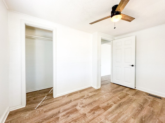 unfurnished bedroom featuring ceiling fan, light hardwood / wood-style floors, a closet, and a textured ceiling