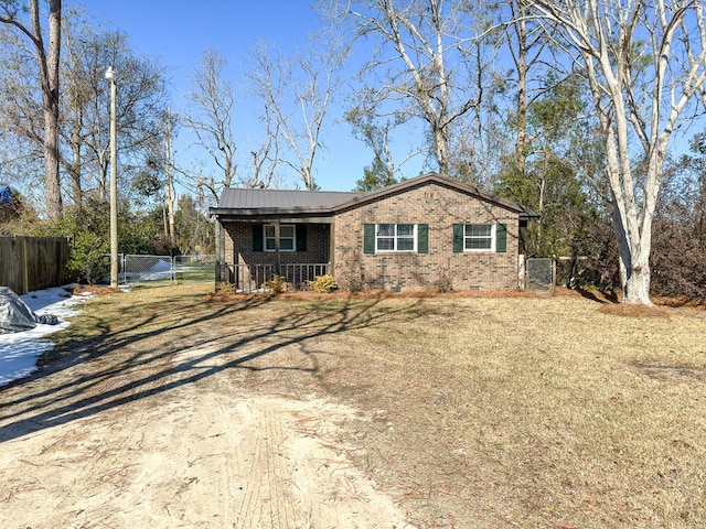 ranch-style house featuring covered porch and a front yard