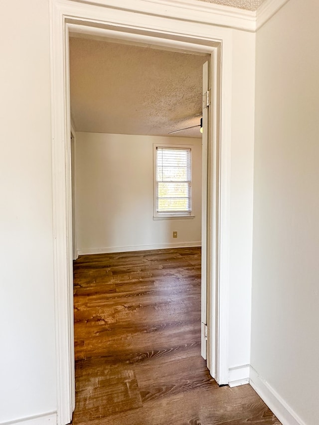 hallway featuring dark wood-type flooring and a textured ceiling