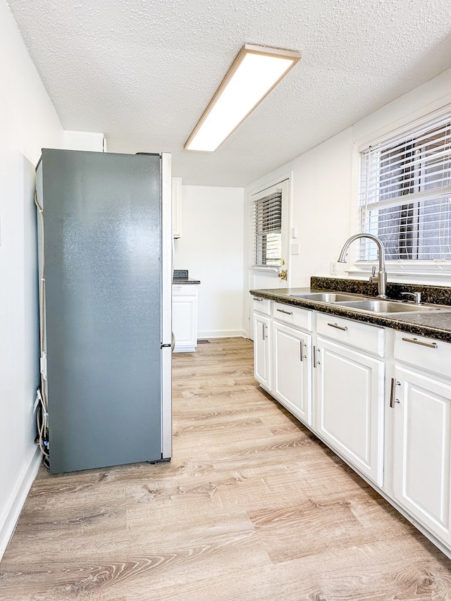 kitchen featuring white cabinetry, sink, stainless steel fridge, and a textured ceiling