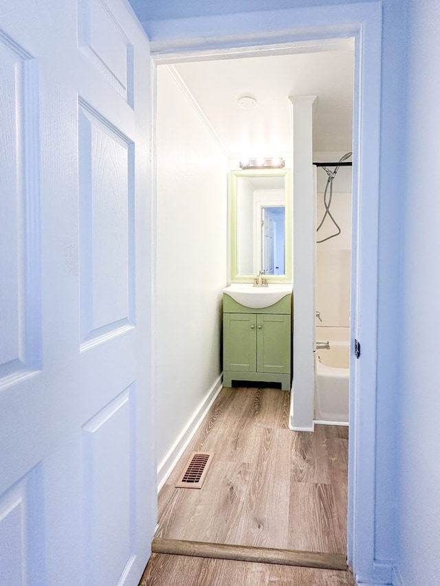 bathroom with vanity, hardwood / wood-style floors, crown molding, and shower / bathtub combination