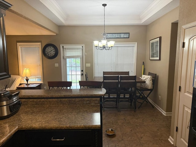 kitchen with ornamental molding, a tray ceiling, and hanging light fixtures