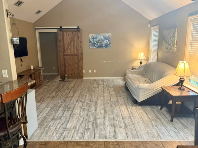 living room with hardwood / wood-style flooring, high vaulted ceiling, and a barn door