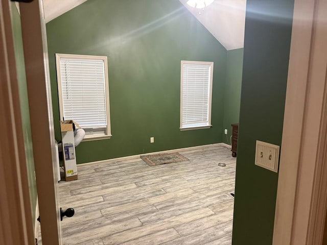 spare room featuring vaulted ceiling and light hardwood / wood-style flooring