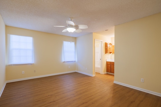 unfurnished room with ceiling fan, a textured ceiling, and light wood-type flooring