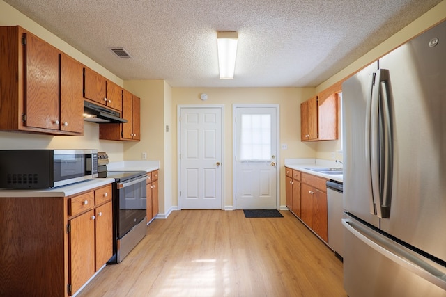 kitchen featuring a textured ceiling, sink, stainless steel appliances, and light hardwood / wood-style flooring