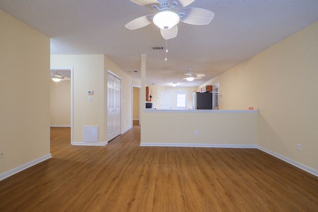 unfurnished living room with ceiling fan, hardwood / wood-style floors, and a textured ceiling