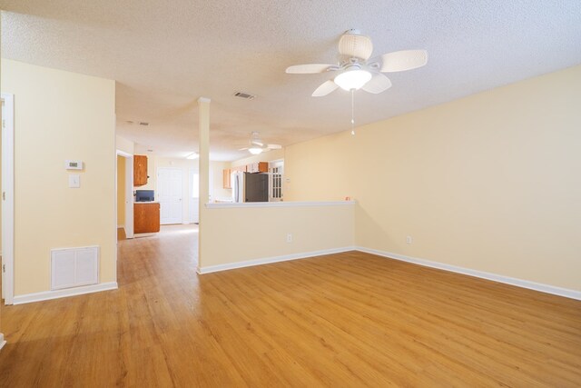 empty room with a textured ceiling, light hardwood / wood-style floors, and ceiling fan