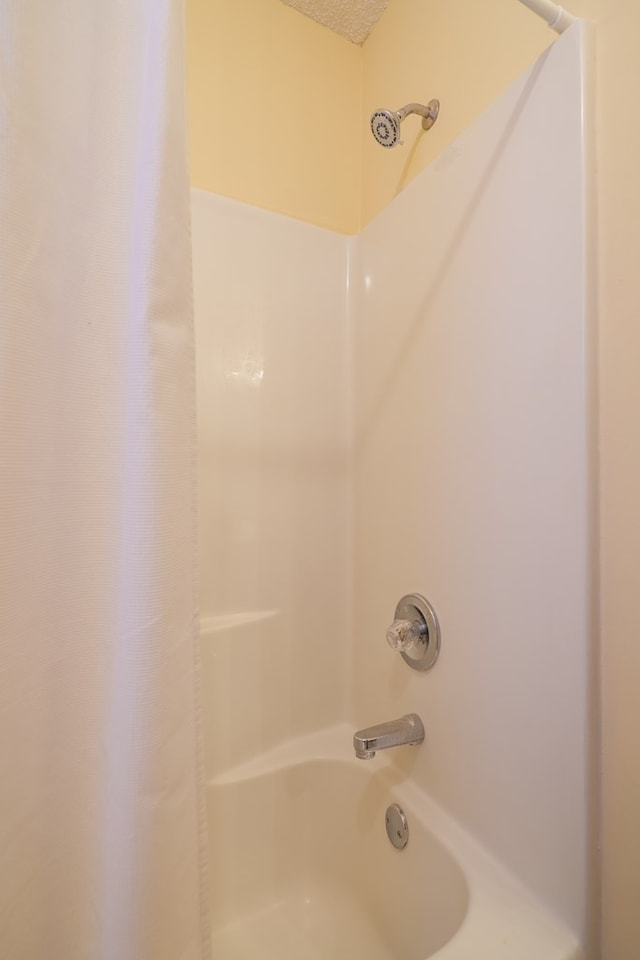 bathroom with shower / bath combination with curtain and a textured ceiling