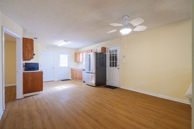 kitchen with stainless steel fridge, ceiling fan, a textured ceiling, and light wood-type flooring