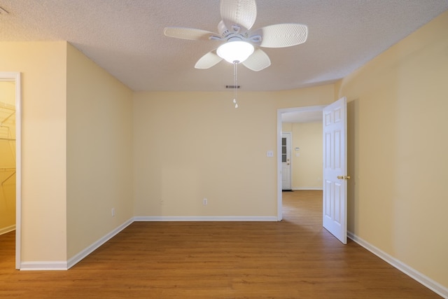 empty room featuring ceiling fan, wood-type flooring, and a textured ceiling