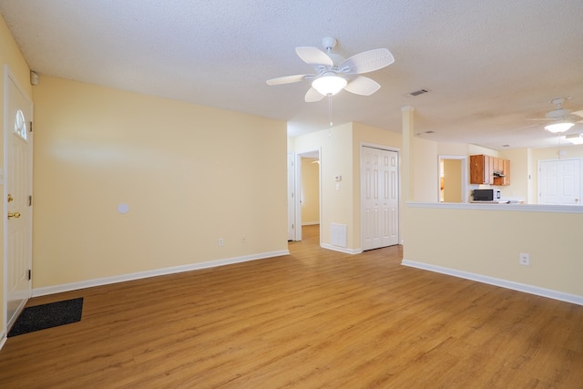 unfurnished living room with a textured ceiling, light wood-type flooring, and ceiling fan