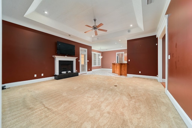 unfurnished living room with light carpet, a tray ceiling, ceiling fan, and ornamental molding