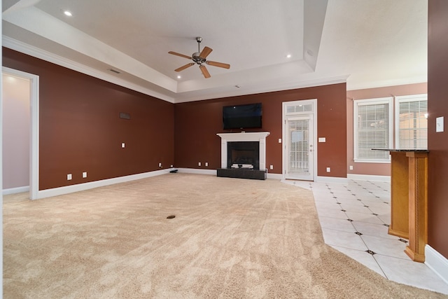 unfurnished living room with light carpet, a tray ceiling, ceiling fan, and crown molding