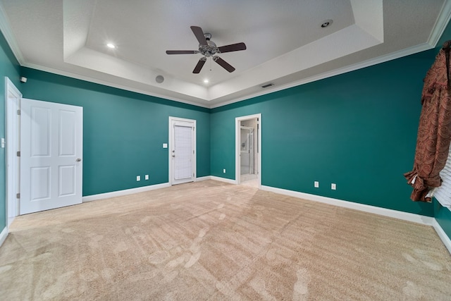 carpeted empty room with a tray ceiling, crown molding, and ceiling fan