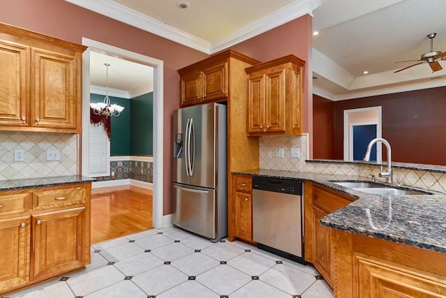 kitchen with sink, dark stone countertops, appliances with stainless steel finishes, ceiling fan with notable chandelier, and ornamental molding