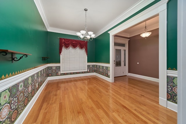 unfurnished dining area featuring crown molding, hardwood / wood-style floors, and a chandelier