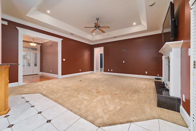 unfurnished living room with ceiling fan, crown molding, light carpet, and a tray ceiling