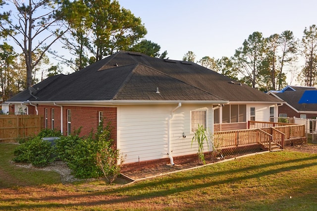 back of property with a deck and a lawn