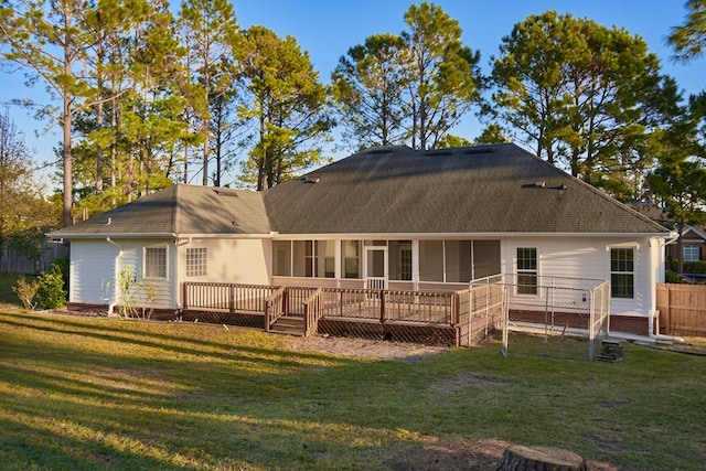 back of property with a lawn, a sunroom, and a deck