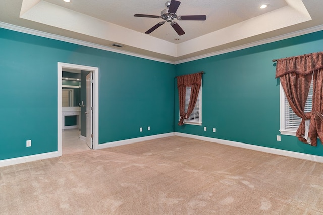 carpeted empty room featuring ceiling fan, ornamental molding, a textured ceiling, and a tray ceiling