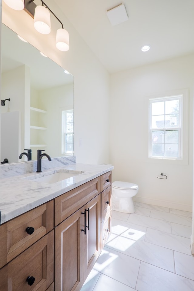 bathroom with toilet, a healthy amount of sunlight, vanity, and baseboards