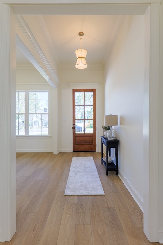 entryway with ornamental molding, baseboards, and light wood-style floors