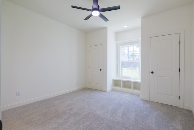 unfurnished bedroom featuring light carpet, baseboards, and a ceiling fan