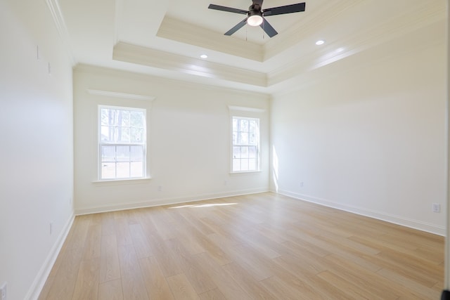 spare room featuring ceiling fan, light wood-style flooring, ornamental molding, a raised ceiling, and baseboards
