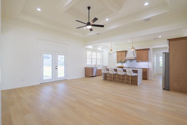 kitchen featuring custom exhaust hood, a raised ceiling, light countertops, brown cabinetry, and stainless steel appliances