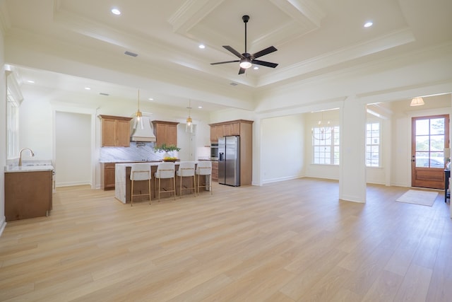 kitchen with a kitchen breakfast bar, stainless steel fridge, open floor plan, a raised ceiling, and light wood finished floors