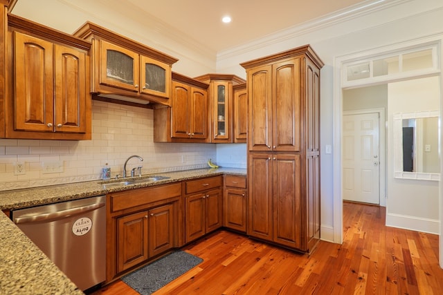 kitchen with light stone countertops, dishwasher, dark wood-type flooring, sink, and ornamental molding