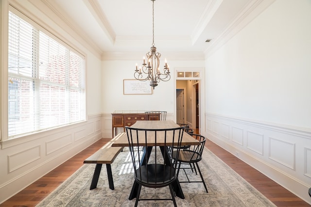 dining room with a healthy amount of sunlight, an inviting chandelier, a tray ceiling, and hardwood / wood-style flooring