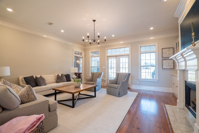 living room featuring crown molding, wood-type flooring, a tile fireplace, and a notable chandelier