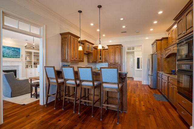 kitchen with pendant lighting, black appliances, dark wood-type flooring, built in shelves, and a breakfast bar area