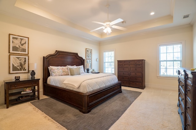 carpeted bedroom with ceiling fan, ornamental molding, and a raised ceiling