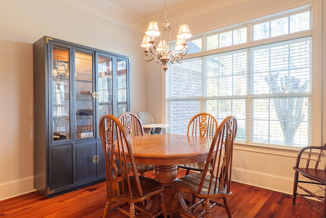 dining area with dark wood-type flooring, an inviting chandelier, and ornamental molding